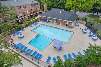 A pool surrounded by blue lounge chairs and a small building.